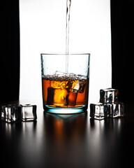 Front vertical view silhouette of whiskey poured out on a glass and ice cubes