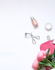 Beauty lifestyle concept frame on the white background with cosmetics and peony flowers. Top view. Copy space