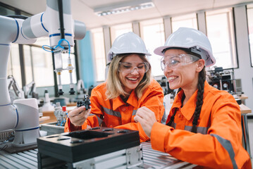 Robotic engineering and technician women working together to repairing robot arm in welding industry. Technician maintenance AI robot part in laboratory.