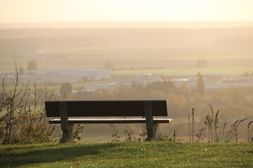 banc vide devant un paysage à l'aube dans la brume
