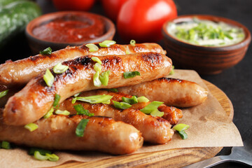 Delicious sausages on a wooden board with various sauces and fresh vegetables on a wooden table. c