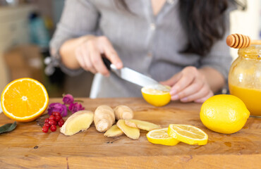 Making healthy ginger tea with lemon and honey on wooden table close-up