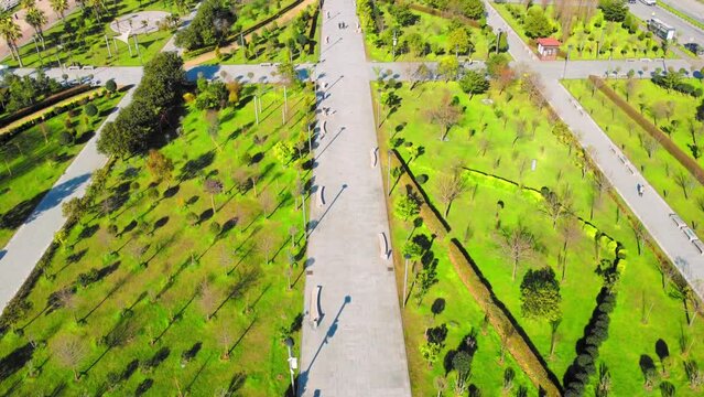 Resort town of Batumi in Georgia. Aerial view of green park on sunny day against background of sea. Lehi and Maria Kaczynski Park in city. Beautiful green landscaping. Infrastructure, mountains