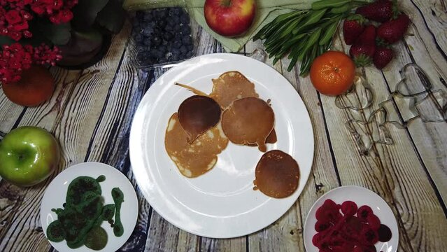 Child arranging mini colorful pancakes in the plate. sorting colors, kids activity, creative breakfast. High quality 4k footage