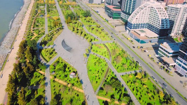 Resort town of Batumi in Georgia. Aerial view of green park on sunny day against background of sea. Lehi and Maria Kaczynski Park in city. Beautiful green landscaping. Infrastructure, mountains