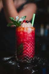 Bartender pouring icing sugar over fruit mojito in a pub