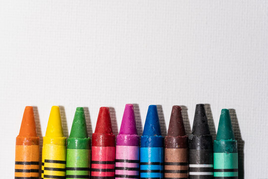Crayons lined up in rainbow on white background, multicoloured wax pencils, children's multi-colored wax crayons for drawing on a white sheet, creativity concept