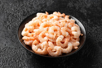 Ready to eat shrimps, prawns in black bowl on rustic background