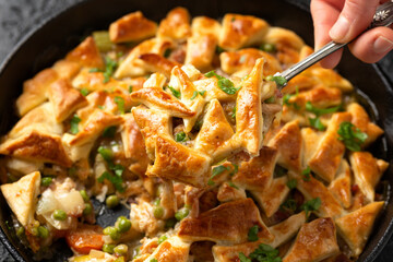 Chicken pot pie with bacon and puff pastry served in cast iron pan. Comfort food concept.