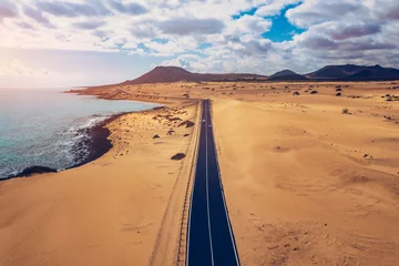 Photo sur Plexiglas les îles Canaries Fuerteventura, Corralejo sand dunes nature park. Beautiful Aerial Shot. Canary Islands, Spain. Aerial view of an empty road through the dunes at the sunset. Fuerteventura, Canary Islands, Spain.