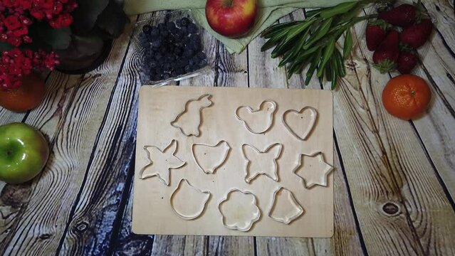 cookie cutters assemblink on the wooden chopping board on the wood surface surrounded by fruits. High quality 4k footage