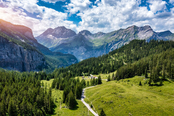 Panoramic view of idyllic mountain scenery in the Alps with fresh green meadows in bloom on a beautiful sunny day in summer, Switzerland. Idyllic mountain landscape in the Alps with meadows in summer. - 595661144
