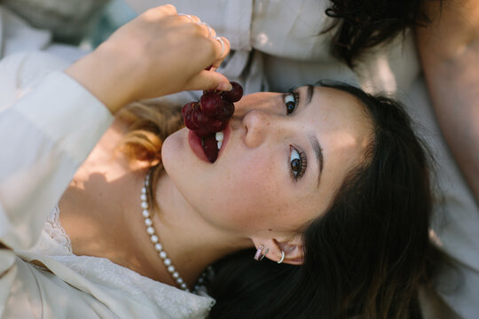 Charming woman eating grapes and looking at camera