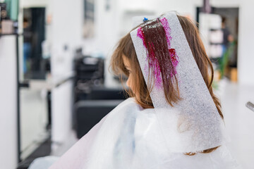 Girl sitting in salon with hair in pink dye