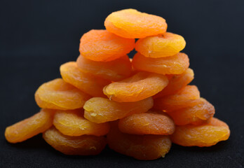 A bunch of dried apricots on a black background. Delicious dried fruits.