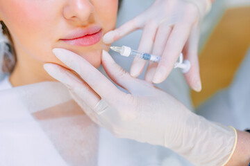 Lip augmentation and correction procedure in a cosmetology salon. The specialist makes an injection...