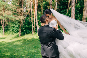 Happy wedding couple, the groom admires the happy bride, holds the bride in his arms and whirls...