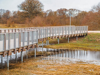 spring in nature, walking path above the water in Latvia. wooden bridge with metal mesh