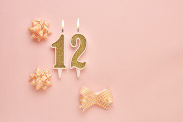 Number 12 on a pastel pink background with festive decorations. Happy birthday candles. The concept of celebrating a birthday, anniversary, important date, holiday. Copy space. banner