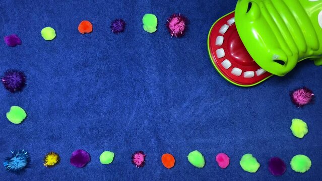 Craft ideas, intro stop motion. Pom pomps around the crocodile on the blue surface. High quality 4k footage