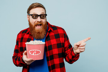 Young fun ginger man in 3d glasses wear casual clothes watch movie film hold bucket of popcorn in...
