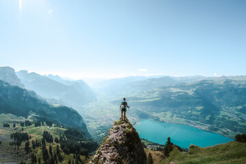 A sporty woman enjoys the view from a beautiful vantage point on Walensee lake in the morning....