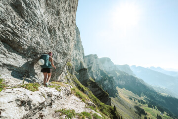 Athletic woman walks on hike trail below steep rock wall with amazing view on the Churfürsten...