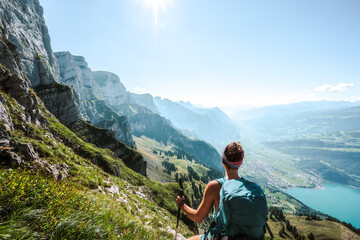 Sporty woman enjoys epic view on the Churfürsten mountain range from hike trail below steep rock wall. Schnürliweg, Walensee, St. Gallen, Switzerland, Europe. - obrazy, fototapety, plakaty