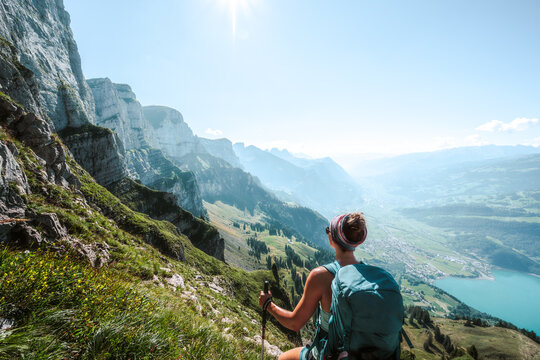 Athletic woman enjoys scenic view on the Churf&uuml;rsten mountain range from hike trail below steep rock wall. Schn&uuml;rliweg, Walensee, St. Gallen, Switzerland, Europe.