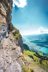 Sporty woman hikes along steep rocky hike trail with amazing view on lake Walensee at noon....