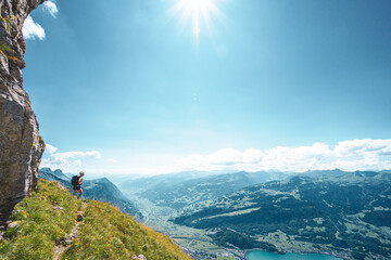 Mountaineer at hike trail on steep slope enjoys amazing view on Walensee. Schn&uuml;rliweg, Walensee, St. Gallen, Switzerland, Europe.