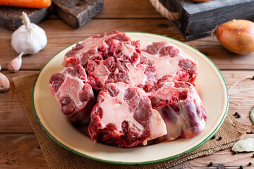 Pieces of raw oxtail and spices for cooking on a wooden board on the table