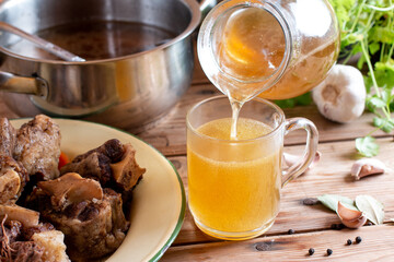 Glass jar with yellow fresh bone broth o on wooden table. Healthy low-calories food is rich in vitamins, collagen and anti-inflammatory amino acids