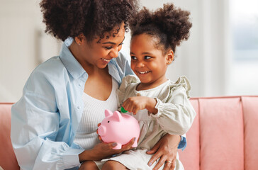 financial education. african american family, mother and child daughter with pig piggy bank counting savings at home  .