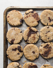 Homemade chocolate stuffed cookies on a parchment lined baking sheet, vanilla and chocolate cookies, thick vanilla cookies with a chocolate filling
