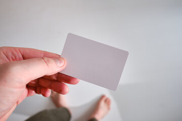 Obraz premium A man holds a business card close-up on a light background. Place for text. Mockup