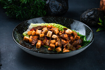 Hot beef goulash with beans, cucumbers, onions and croutons in a lettuce leaf.