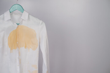 Fototapeta premium Women's office white shirt with a stain of coffee on a white background. Copy space. 
