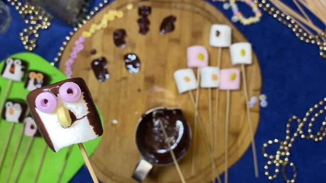 Creative food decoration. Sweet marshmallow penguin sliding over chopping board Desserts and sweets. High quality 4k footage
