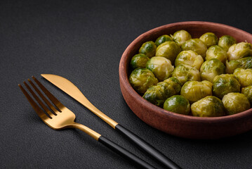 Delicious boiled Brussels sprouts on a ceramic plate on a dark concrete background