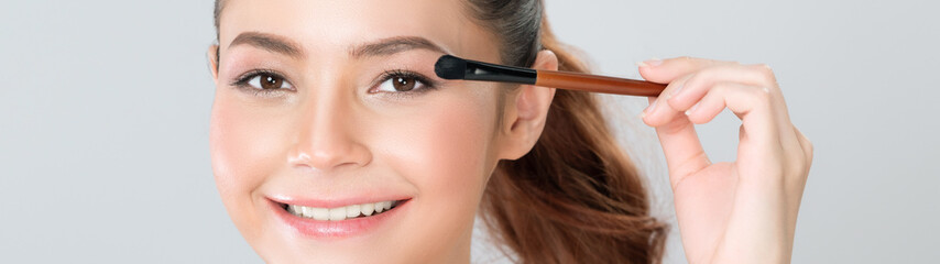 Closeup beautiful girl with flawless applying glamorous eye shadow makeup with eyeliner brush....