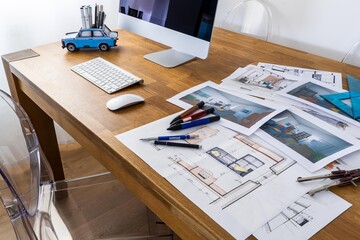 Interior design sketching, designer's desk with computer, sketches, prints, and drawing tools