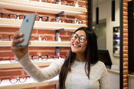 Happy female in eyewear taking selfie in optical shop