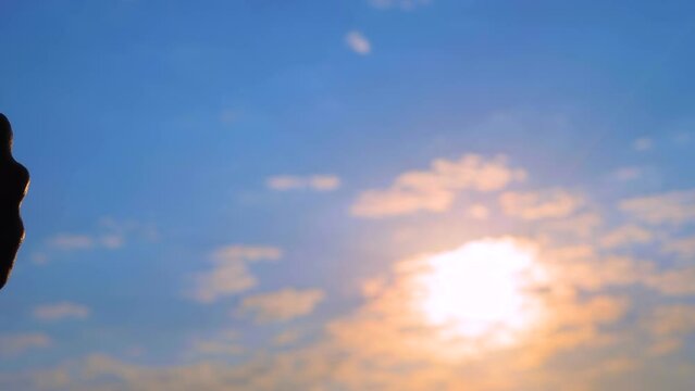 Man and woman hands silhouettes are bumping fists against the sunset or sunrise sky - sun lens flares, close up view. Approval, informal greeting, agreement, giving dap and teamwork concept