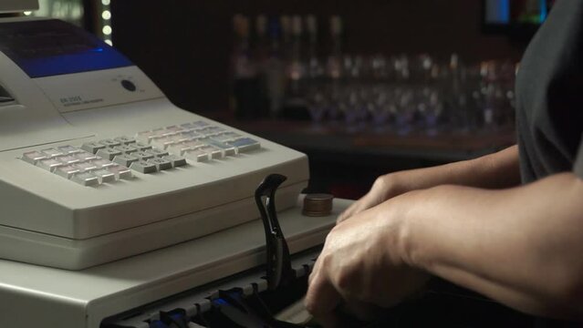 Persona que utiliza la caja registradora, contando dinero, billetes y monedas