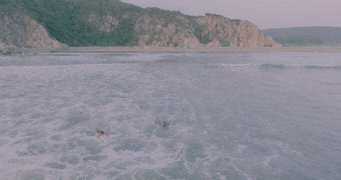 Young people surfing waves at La Bocana beach in Huatulco Oaxaca in the afternoon. Tourism and travel concept. Drone view. 4k video.