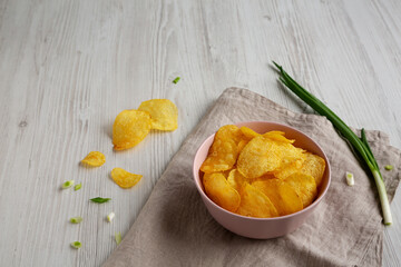 Crunch Green Onion Potato Chips in a Pink Bowl, side view. Copy space.