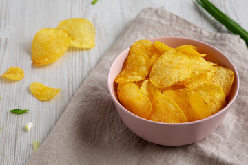 Crunch Green Onion Potato Chips in a Pink Bowl, side view. Close-up.