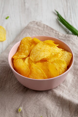 Crunch Green Onion Potato Chips in a Pink Bowl, side view. Close-up.