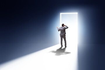 Businessman entering backlit door in escape concept